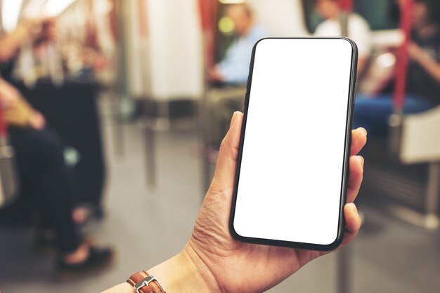Mockupbeeld van vrouwenhanden die zwarte mobiele telefoon met leeg scherm in metro houden