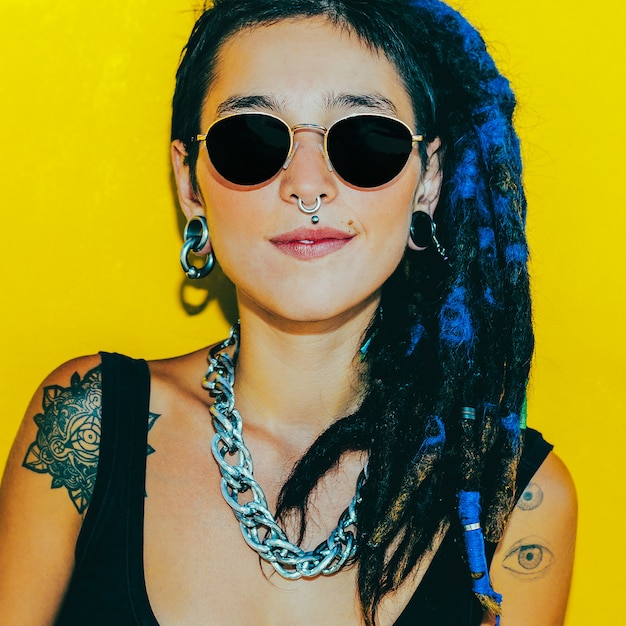 Mode best cool meisje met dreadlocks en piercings over kleurrijke gele muur