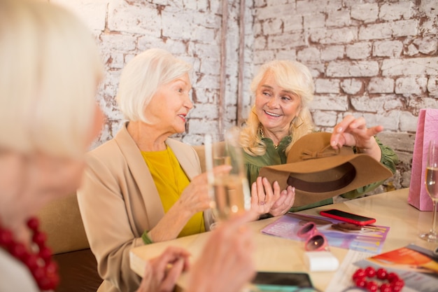 Mode. drie vrouwen hebben plezier tijdens het passen van een nieuwe hoed