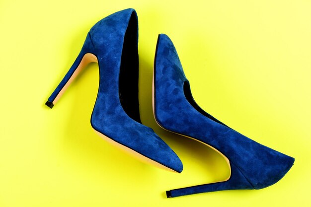 Mode en beauty concept Paar blauwe suède schoenen met hoge hakken Vrouwelijke formele schoenen bovenaanzicht Elegante blauwe schoenen geïsoleerd op gele achtergrond