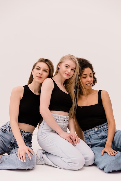 Mode foto van drie mooie blanke en afro vrouwen kijken in verschillende richtingen poseren op witte achtergrond Lifestyle schoonheid en multiraciale vriendschap concept