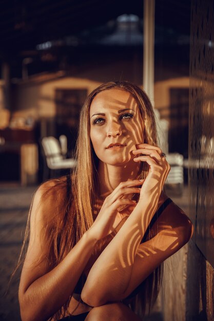 Mode foto van mooie gebruinde vrouw met rood haar in elegante zwarte bikini ontspannen naast een zwembad