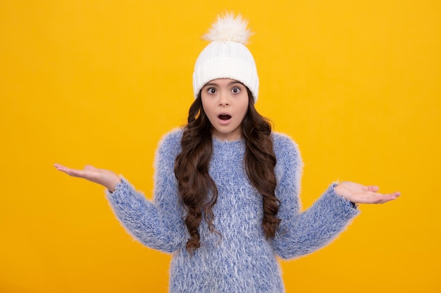 Foto mode gelukkige jonge vrouw in gebreide muts en trui met plezier over kleurrijke blauwe achtergrond verrast gezicht verrassing emoties van tiener meisje