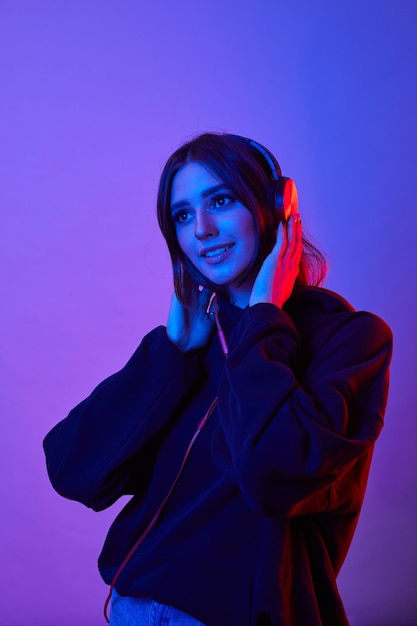 Mode hipster vrouw draagt koptelefoon luisteren naar muziek over kleur neon achtergrond in de studio.