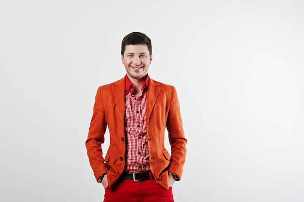 Mode lachende jonge man in oranje pak en rode broek casual pose