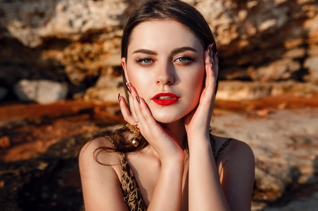 Mode openluchtportret van sexy mooie elegante vrouw met lang haar, gekleed in een luxe avondjurk die zich voordeed op het zomerstrand