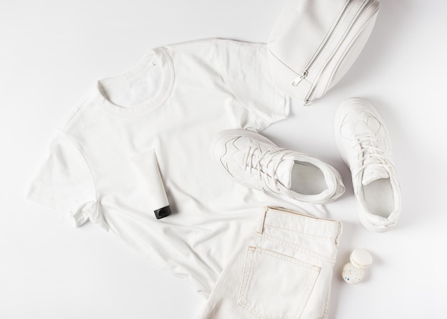 Mode plat met witte t-shirt sneakers heuptas en accessoires monochroom concept casual look Kopieer ruimte bovenaanzicht