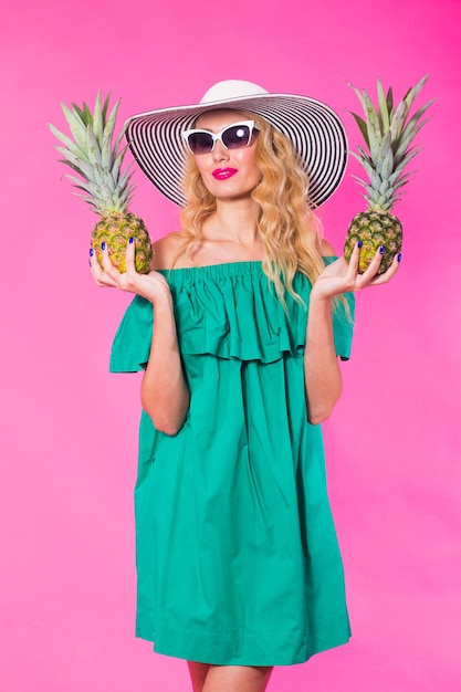 Mode portret jonge mooie vrouw met ananas op roze achtergrond