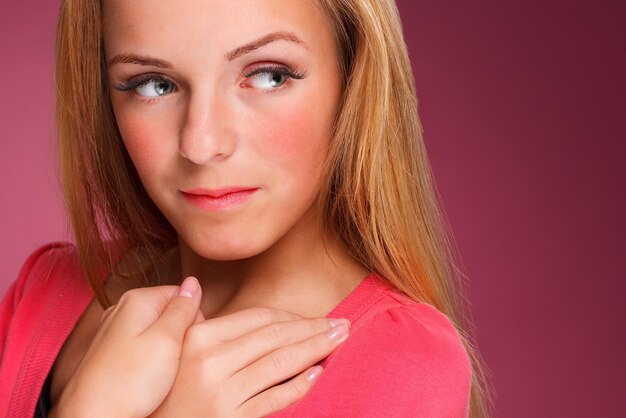 Mode portret van elegante jonge vrouw met blond krullend haar op roze achtergrond