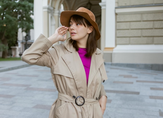Mode portret van jonge vrouw in een vilten hoed en herfst trenchcoat in de stad
