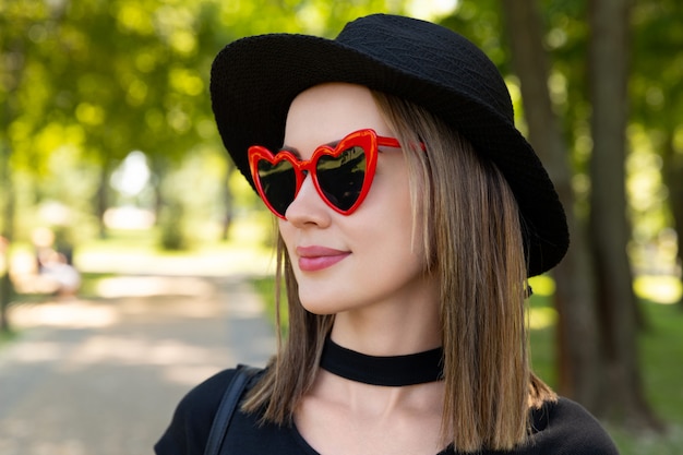 Mode portret van mooie vrouw in zwart t-shirt en rode rok wandelen in het park