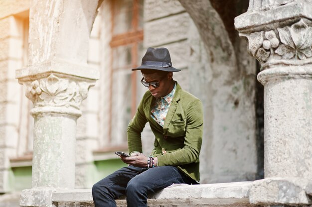 Mode portret van zwarte Afrikaanse Amerikaanse man op groen fluwelen jas en zwarte hoed