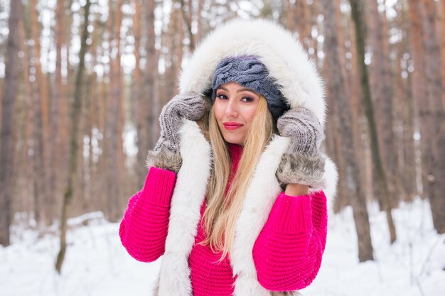 Mode, schoonheid en mensen concept - portret van blonde jonge vrouw in bontjas op winter achtergrond