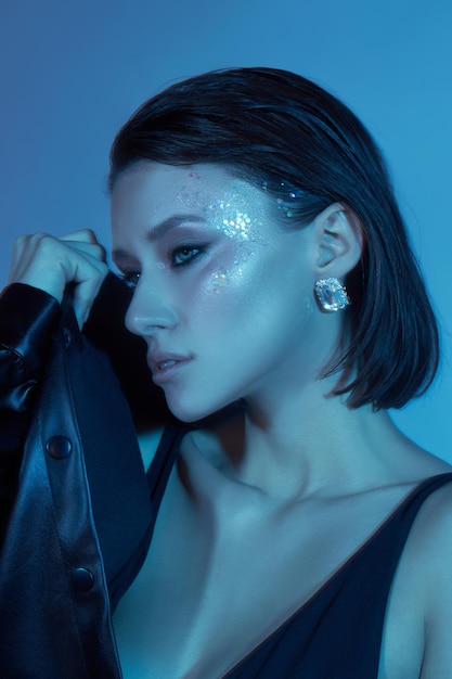 Mode sexy jonge vrouw neonlicht poseren in de studio schoonheid make-up portret van een vrouw blauw licht Slim lichaam zwart lederen jas en ondergoed