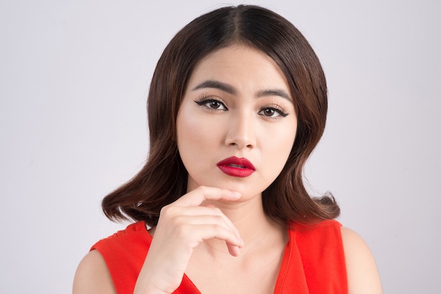 Mode studio portret van prachtige sensuele Aziatische vrouw met donker haar draagt elegante rode jurk