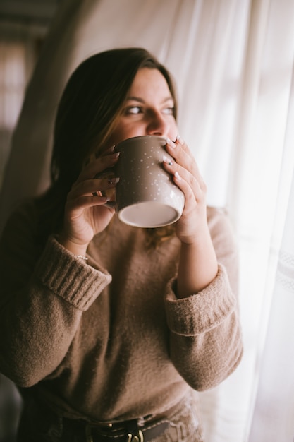 Mode vrouw genieten van koffie of thee moment. Koffiekopje in meisjeshanden. Vrouw met kop warme drank. Winter kopje drank. Ontspannend concept.