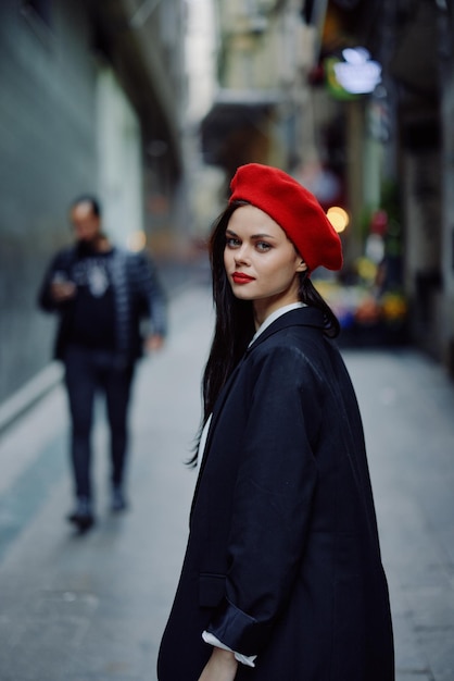 Mode vrouw portret wandelende toerist in stijlvolle kleding met rode lippen lopend door de smalle straat van de stad reizen filmische kleur retro vintage stijl dramatisch