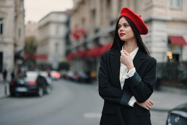 Mode vrouw staand op straat voor de stad in stijlvolle kleding met rode lippen en rode baret reizen filmische kleur retro vintage stijl stedelijke mode levensstijl