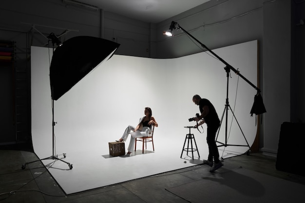 Modefotografie in een fotostudio. Professionele mannelijke fotograaf die foto's maakt van een mooi vrouwenmodel op camera, backstage