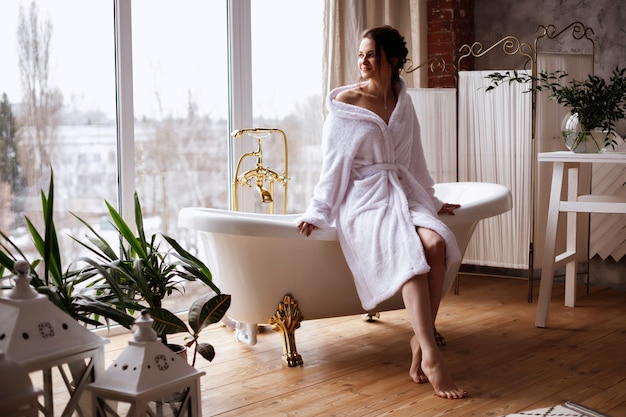 model in a bathrobe sits on a bath