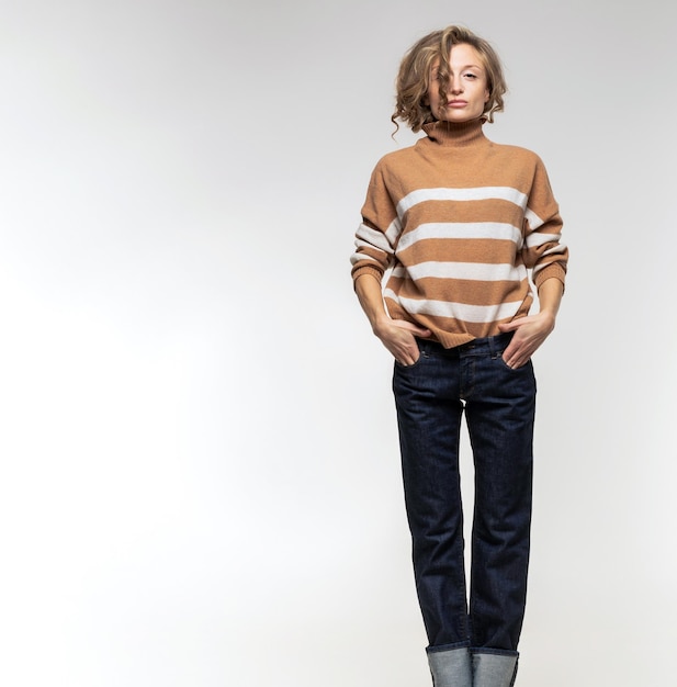 A model in a brown sweater with stripes and jeans