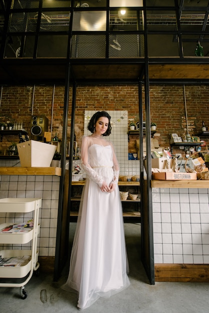 Bruna modello in capelli corti in posa in un abito da sposa bianco