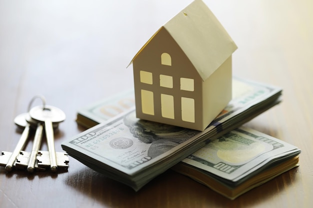 Model of cardboard house with key and dollar bills Building loan real estate cost of housing or buying a new home concept