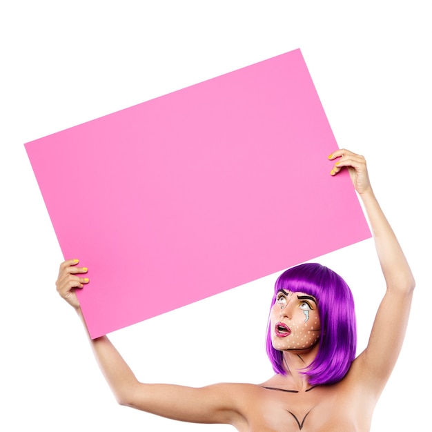 Model in creative image with pop art makeup is holding pink blank board isolated on white