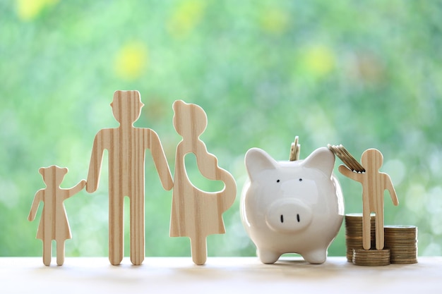 Model family with piggy bank and stack of coins money on natural green background