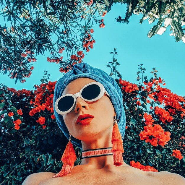 Model in fashion beach accessories. Head scarf, sunglasses and earrings. Tropical fashion outfit