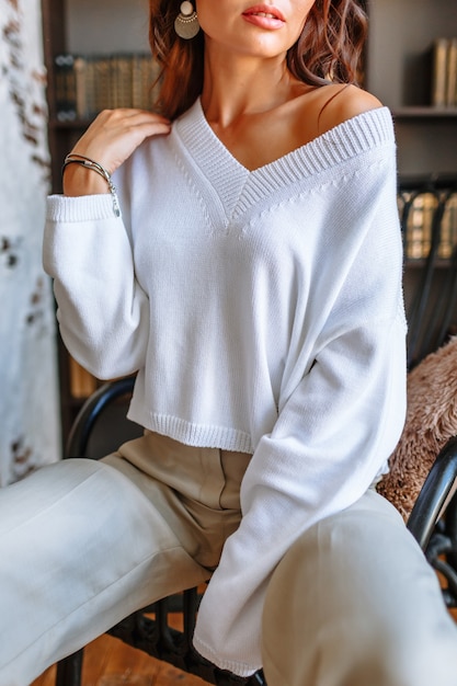 Model girl in a white jacket sitting on a chair