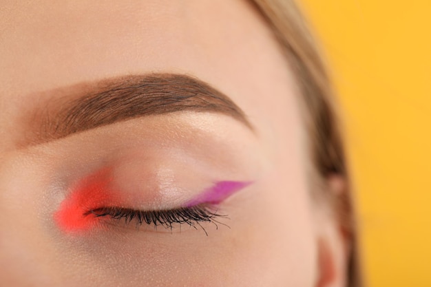 Model girl with makeup on yellow background, close up