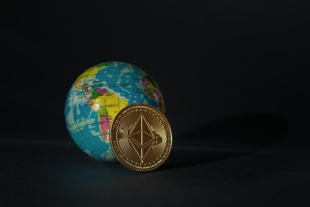 A model of the globe and a digital currency coin on a black background.