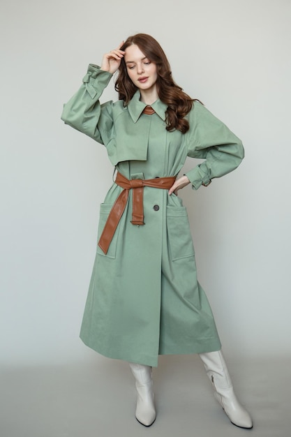 A model in a green coat with a brown leather belt Clothing advertising