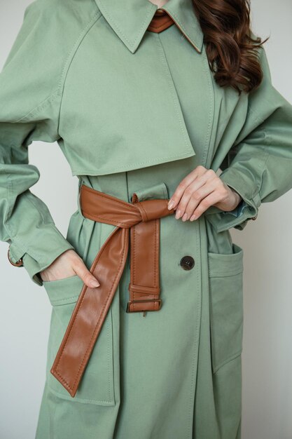 A model in a green coat with a brown leather belt Clothing advertising