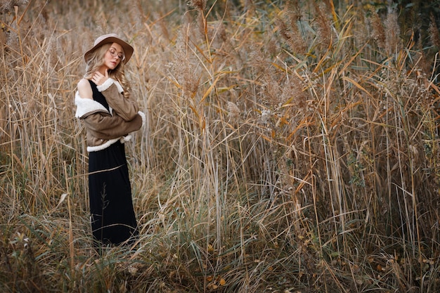 Model in hat and jacket fall posing in nature