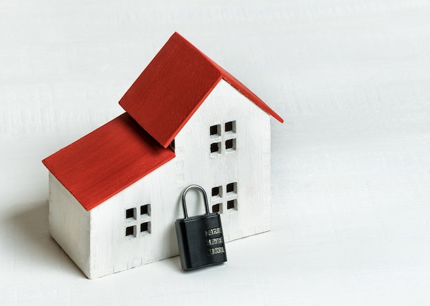 Model home and lock on white background. Home safety protection concept. Closeup