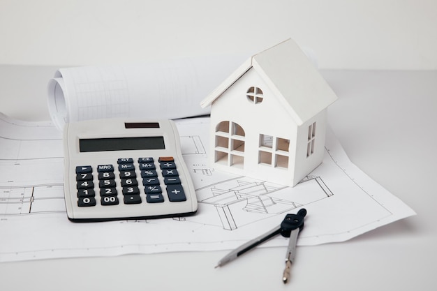 Photo model of house calculator and engineer tools on drawings