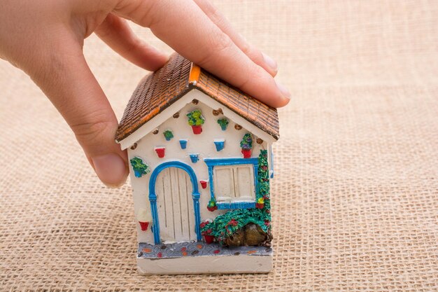 Casa modello e una mano su uno sfondo di colore marrone chiaro