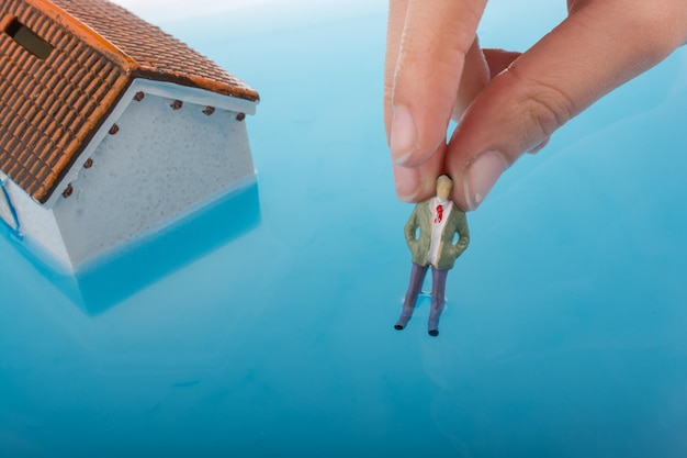 Model house and a man figurines in water