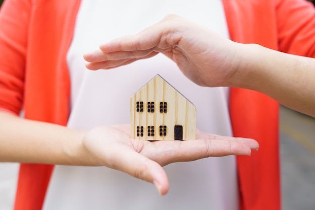 A model house model is placed on The Hands of Asian Business Girl. concept