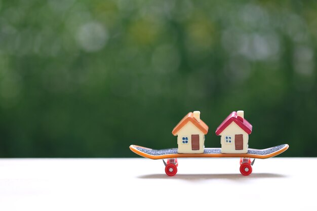 Casa modello su skateboard con sfondo verde naturale, investimento aziendale e concetto immobiliare