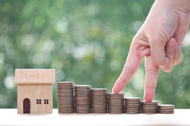 Photo model house and stack of coins money on natural green background