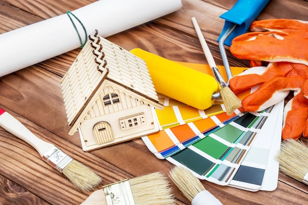 Foto modello di casa con pennelli a rullo di vernice e libro di campioni di colore sul tavolo concetto di miglioramento domestico e riparazione vista dall'alto