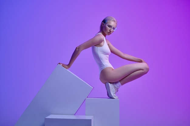 Фото Модель в белой одежде и футуристических очках, лежащих на кубиках. женский человек в стиле виртуальной реальности, технологии будущего