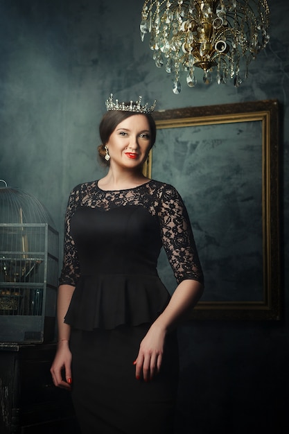 Photo model is posing in a dark studio as a queen