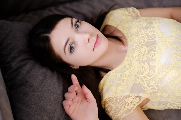Foto model meisje ligt in een gele jurk op de bank rusten met mooie ogen wijd geopend ontspanning