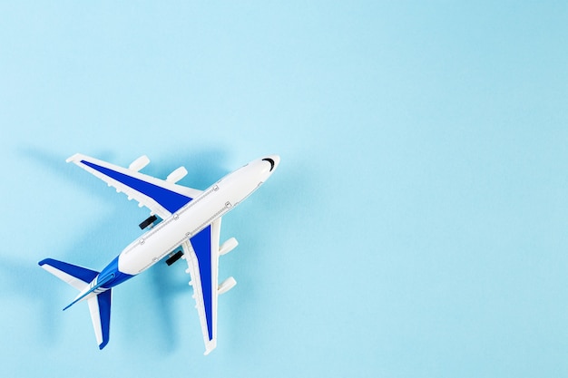 模型飛行機、青いパステルカラーの背景に飛行機。夏の旅行や休暇のコンセプト。ミニチュアおもちゃの飛行機のフラットレイ。トレンディなミニマルスタイル、コピースペース
