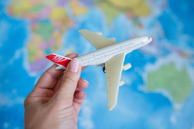地図の背景に女性の手で模型飛行機旅行観光空の旅