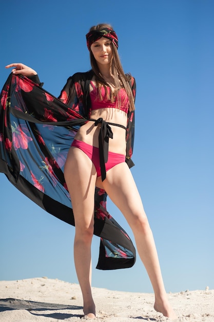 A model poses on a beach wearing a black and red bikini.